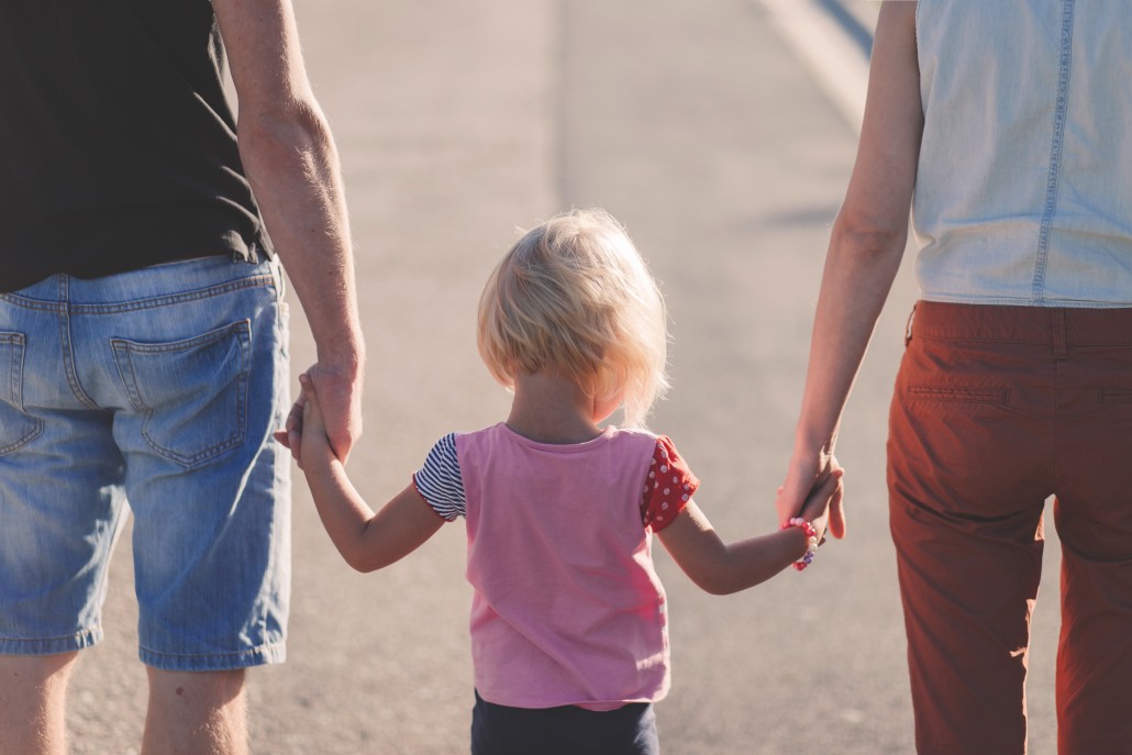 parents holding their small child by their hands